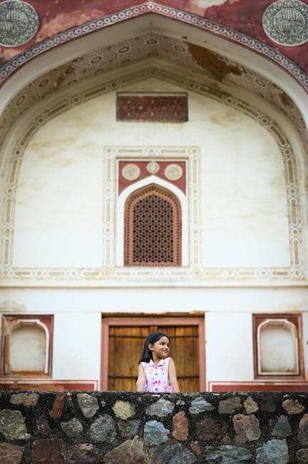 A young girl stands in front of a historical building with intricate design details.